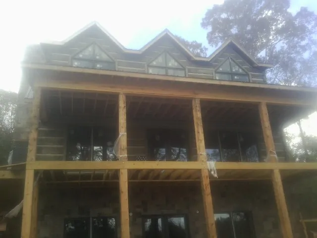 Dormers and porch framing on a large log home under construction — Roof Coating work by our crew in Shiloh